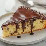 Slice of cornbread chocolate cake with a rich chocolate glaze on a white plate
