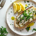 A plated dish showcasing how do you eat sardines from a can, served on rustic bread with garnishes