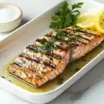 How should king salmon be cooked? A perfectly plated king salmon fillet garnished with herbs and surrounded by lemon slices