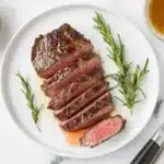 How to reheat leftover tri tip slices served on a modern plate with beef broth on a white marble table