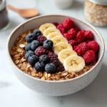 A bowl of oatmeal with fresh berries and bananas on a marble table, showcasing a gluten-free and dairy-free breakfast option