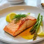 Is king salmon different from salmon? A delicious king salmon fillet on a white plate with roasted asparagus and lemon wedges