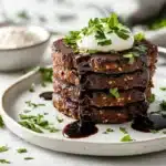 A stack of savory buckwheat cakes flour recipes plated with fresh parsley and sour cream on a white marble table